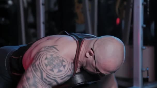 Il bodybuilder professionista allena il muscolo deltoide posteriore su una panchina con i manubri in un club sportivo
. - Filmati, video