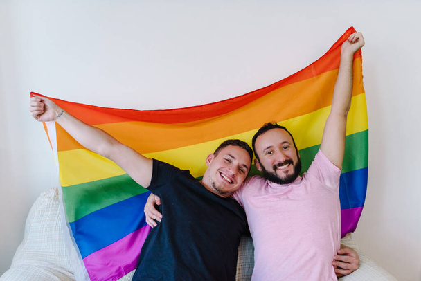 Archivbild von zwei kaukasischen homosexuellen Männern, die sich umarmen und ein Selfie machen. Dahinter steckt eine Katze. - Foto, Bild