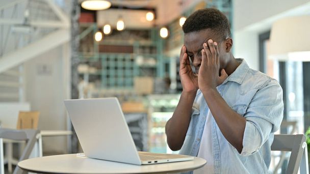 Fleißiger junger Afrikaner mit Laptop hat Kopfschmerzen - Foto, Bild
