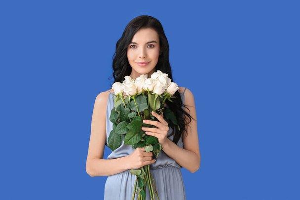 Schöne junge Frau mit einem Strauß Rosen auf farbigem Hintergrund - Foto, Bild
