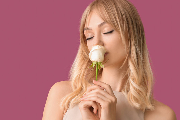 Mooie jonge vrouw met roos op kleur achtergrond - Foto, afbeelding