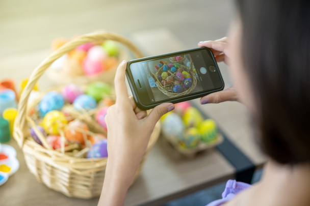 Asian young pretty woman enjoy taking a photo to the colorful fantasy Easter egg by using smartphone. Colorful fancy Easter egg in bucket. The symbolic of Easter egg festival concept. - Foto, Imagem