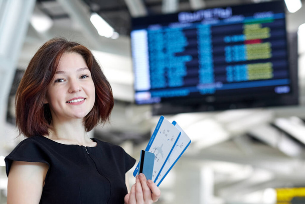 woman information board at airport for buy ticket flight travel vacation in holiday checking online by smartphone - Foto, Imagen