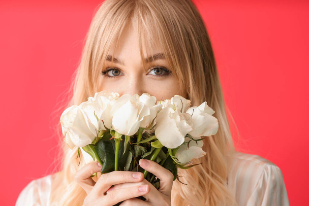 色の背景にバラの花束を持つ美しい若い女性 - 写真・画像