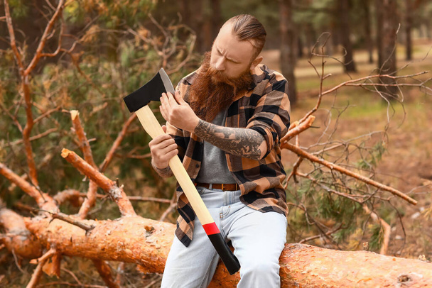 Handsome lumberjack with axe in forest - Фото, зображення