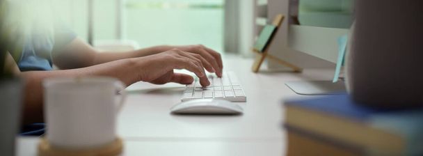 Vue latérale de l'entrepreneur masculin tapant sur l'appareil informatique sur le bureau blanc dans la salle de bureau moderne
  - Photo, image