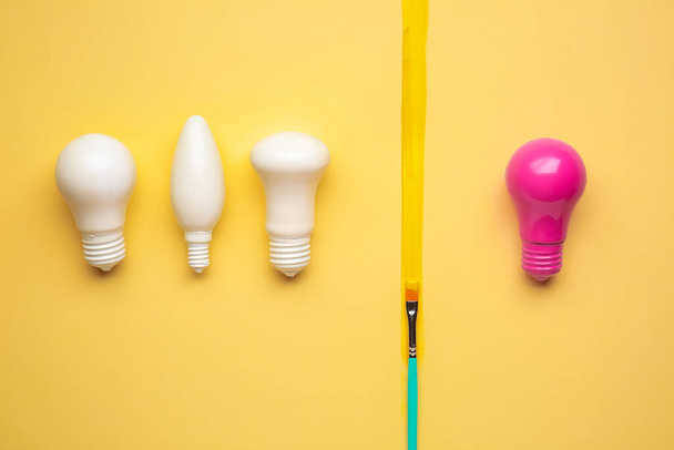 Pink light bulb among white ones on color background. Concept of uniqueness - Foto, Imagen