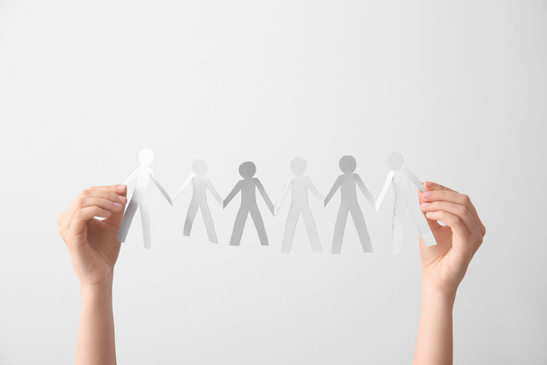 Female hands holding paper human figures on light background. Unity concept - Foto, Imagem