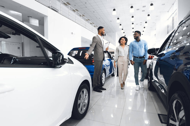 Cheerful Manager Showing Automobile To Customers In Dealership Store - Фото, зображення