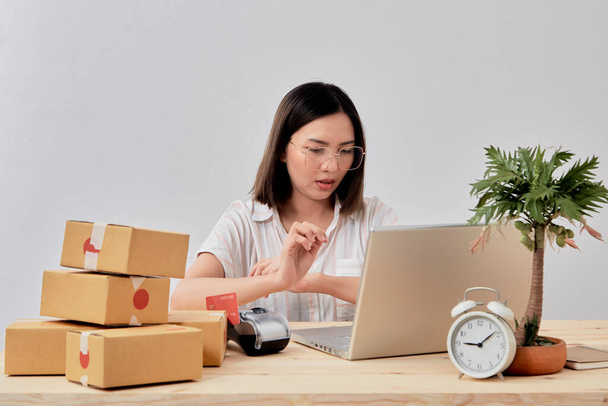 Young attractive asian woman online seller working on laptop computer checking order on internet at home preparing for delivery at from home - Foto, Imagem