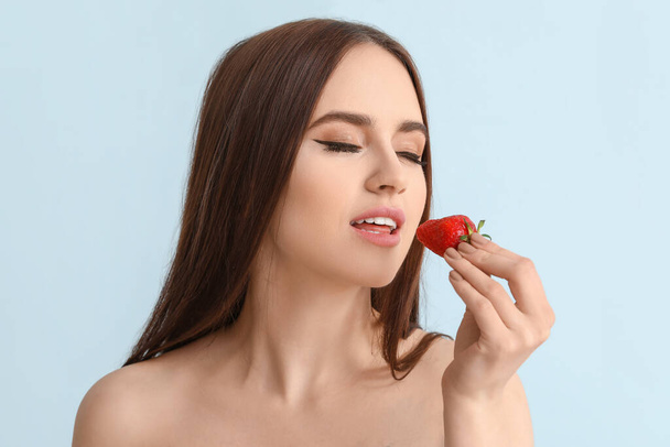 Sexy young woman with strawberry on color background - Фото, изображение