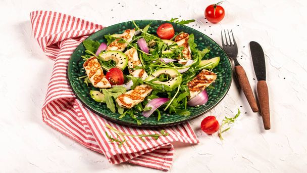 A keleti konyha koncepciója. Ciprusi saláta grillezett Halloumi sajttal, paradicsommal, avokádóval, arugulával. banner menü recept hely szöveg. Lapos fektetés. - Fotó, kép
