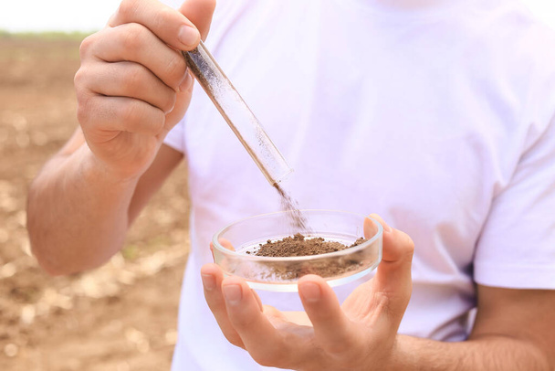 Agronomist with sample of soil in field, closeup - Photo, image