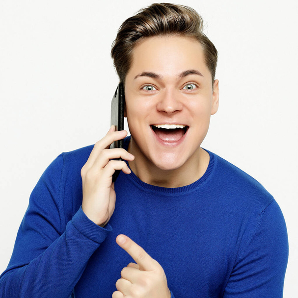 Glücklicher junger Mann im Hemd gestikuliert und lächelt beim Telefonieren - Foto, Bild