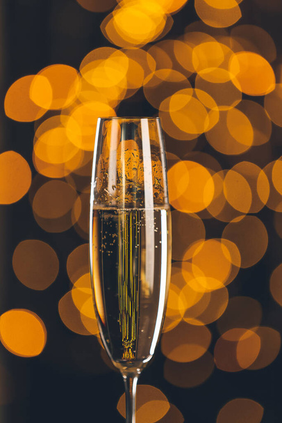 Glas leckerer Champagner auf dunklem Hintergrund mit verschwommenem Licht - Foto, Bild
