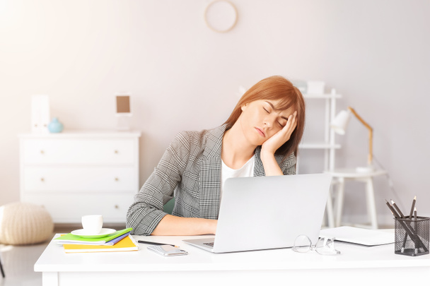 若い女性はオフィスで睡眠不足に苦しんでいます - 写真・画像