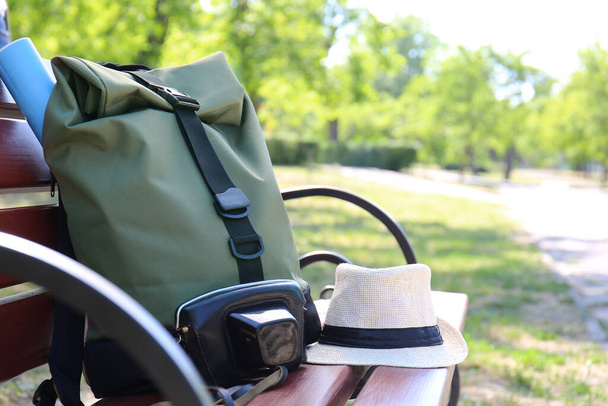 Traveler's backpack and hat on bench in green park - Photo, Image