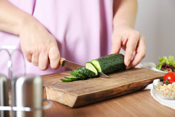 Une femme coupe un concombre. Le processus de fabrication de la salade
 - Photo, image