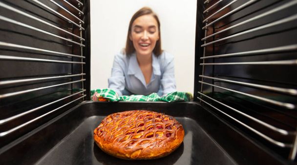 Veselá hospodyňka odstraňuje chutný koláč z trouby - Fotografie, Obrázek