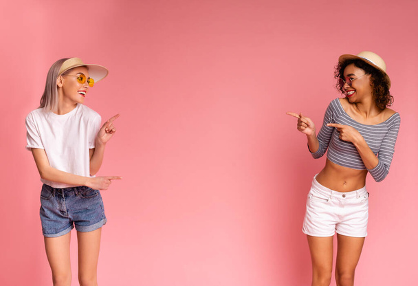 Oferta de verano. Alegre millennial niñas en elegante desgaste apuntando al espacio de copia
 - Foto, imagen