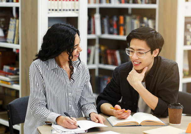 Multicultural couple doing homework in public library - Photo, Image