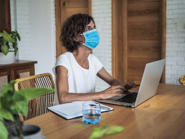 woman wearing mask working with laptop at home, home office and quarantine concept - Foto, afbeelding