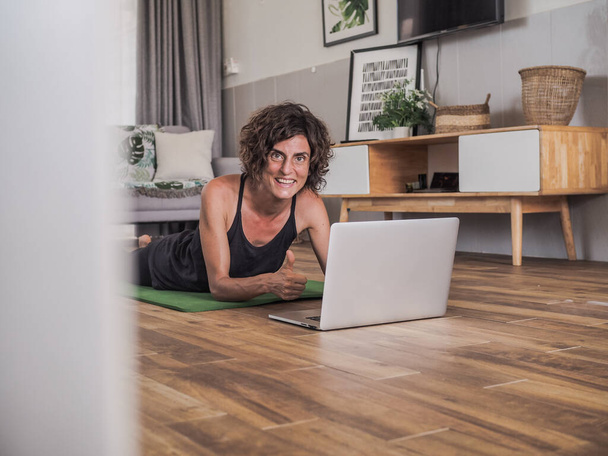 woman practicing yoga at home sitting in front of laptop - 写真・画像