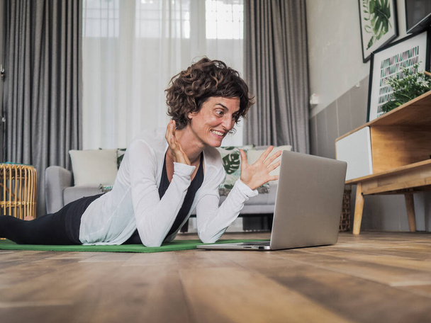 happy woman using laptop at home lying on yoga mat - 写真・画像