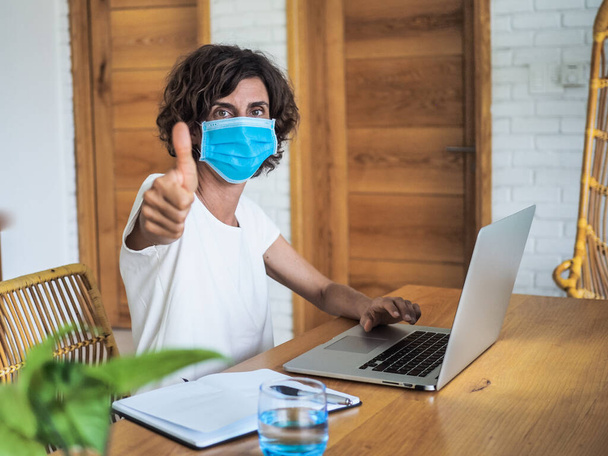 woman wearing mask working with laptop at home, home office and quarantine concept - Foto, immagini