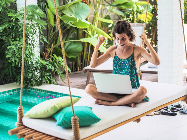woman working online with laptop sitting at a blue water pool - Foto, immagini