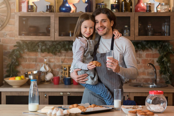 Čas na svačinu. Šťastný táta a malá dcera těší čerstvé domácí pečivo - Fotografie, Obrázek