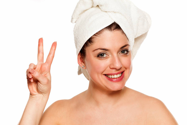 Mladá krásná žena s ručníkem na hlavě na bílém pozadí, ukazující dva prsty - Fotografie, Obrázek