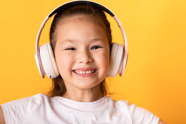 Gülümseyen Asyalı kız kulaklıkla müzik dinlemekten hoşlanıyor. - Fotoğraf, Görsel