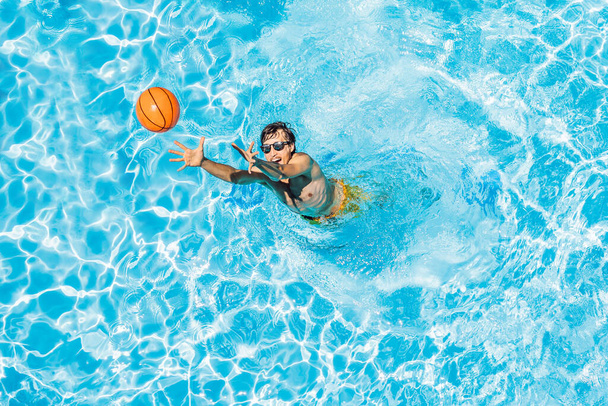 Man play in the pool with a beach ball - Фото, зображення