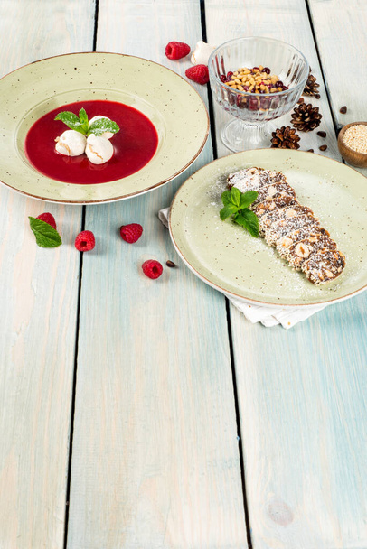 Sweet raspberry and chocolate sausage dessert shot on a white wooden background - Foto, Imagen
