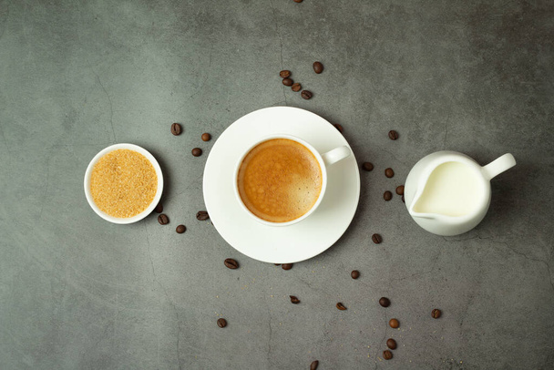 taza de café negro, jarra de leche y granos de café sobre un fondo negro
 - Foto, imagen