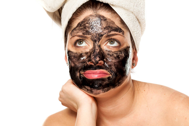 Young unhappy woman with towel on her head posing with black mask on her face - Foto, immagini