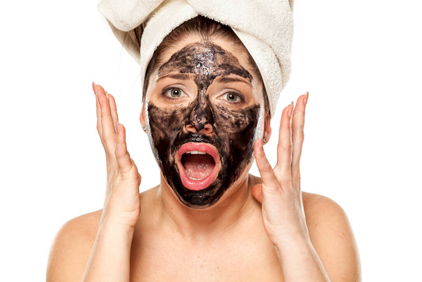 Young unhappy woman with towel on her head posing with black mask on her face - Photo, Image
