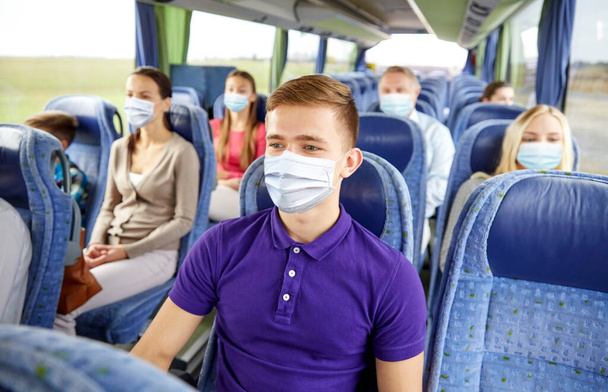 young man in mask sitting in travel bus or train - Foto, Bild