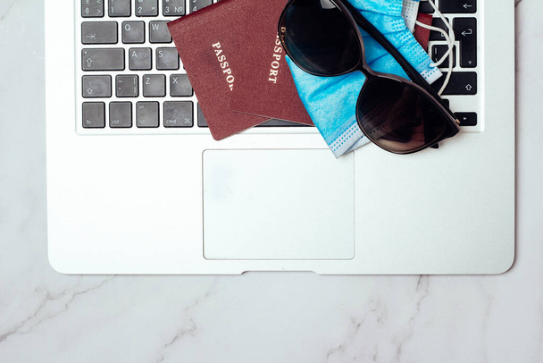 passport sunglasses and mask on computer travel concept - Фото, изображение