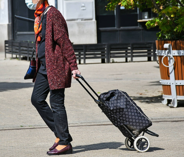 Mujer mayor con un carrito de compras en la calle de la ciudad
 - Foto, Imagen