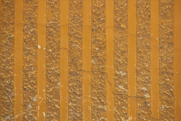 Décoratif fond texture parget. Fragment mural avec motif rayé vertical. Plâtre structurel, surface rugueuse et inégale avec des fissures de couleur jaune orangé
. - Photo, image