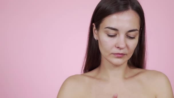 Portrait of beautiful woman applying face cream isolated on pink background - Imágenes, Vídeo