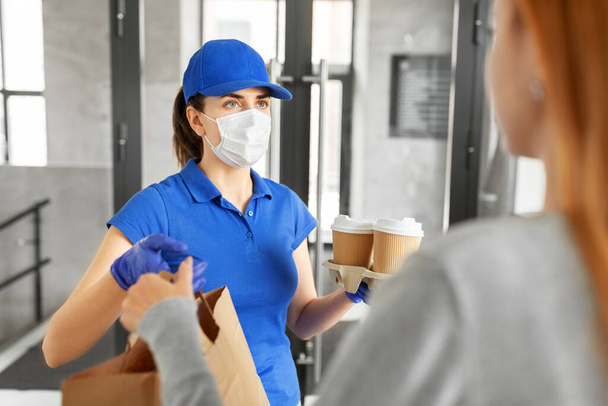 delivery girl in mask giving paper bag to customer - Fotó, kép