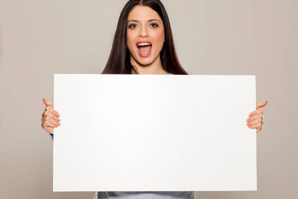 Ευτυχισμένη γυναίκα που δείχνει κενό κενό χάρτινο σημάδι με αντίγραφο χώρου για κείμενο - Φωτογραφία, εικόνα