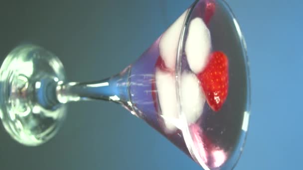 Macro van een professionele barman stopt professionele kristallen ijsblokjes in een glas terwijl hij een alcoholische cocktail klaarmaakt voor klanten aan de bar of discotheek. Verticale video voor smartphones en tablets - Video