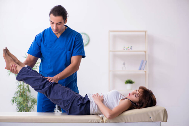 Injured woman visiting young male doctor osteopath - Foto, Imagen