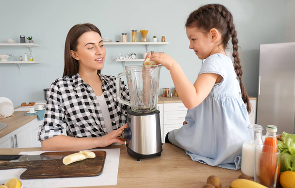 Moeder en dochtertje maken gezonde smoothie in de keuken - Foto, afbeelding