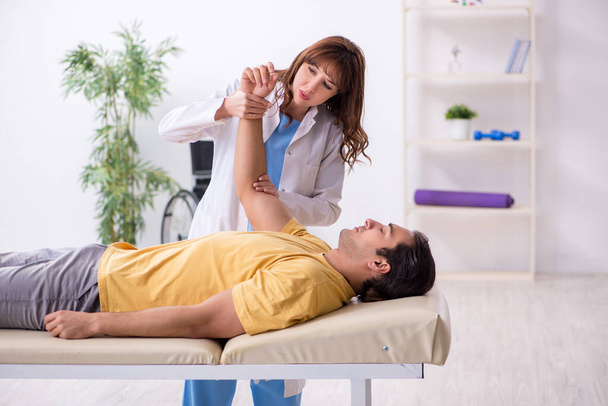 Injured man visiting young female doctor osteopath - Photo, Image