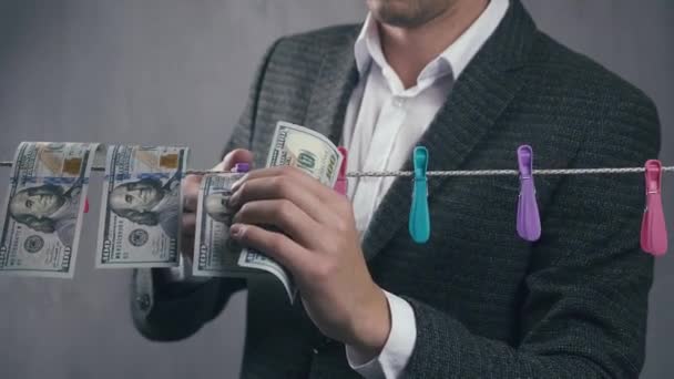 Mannelijke criminele wassers geld. Een man droogt dollarbiljetten aan een touw. Begrip economische criminaliteit. - Video
